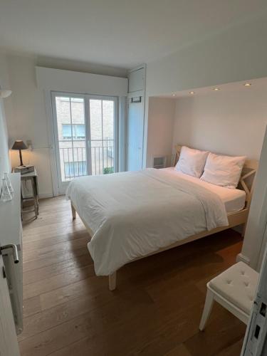 a bedroom with a large bed with white sheets and pink pillows at Mar y sal in Knokke-Heist