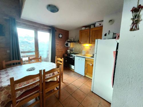 une cuisine avec une table et un réfrigérateur blanc dans l'établissement Appartement 2 pièces + mezzanine, balcon, 6 pers, Plagne Soleil, près des pistes - FR-1-351-151, à La Plagne Tarentaise