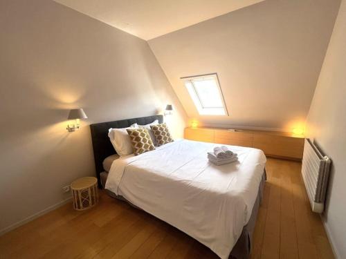 une chambre avec un lit avec des draps blancs et une fenêtre dans l'établissement Comfort & design 2 BR near Place des Vosges, à Paris