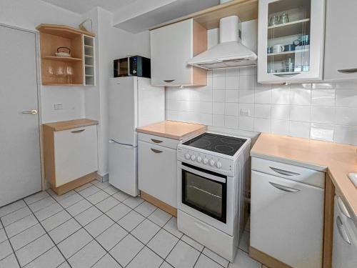 Il comprend une cuisine blanche équipée d'une cuisinière et d'un réfrigérateur. dans l'établissement Pause Paisible à Rueil-Malmaison, à Rueil-Malmaison