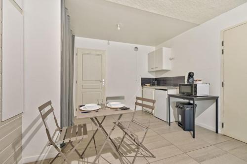 une cuisine avec une table et des chaises et un micro-ondes dans l'établissement Welcome to Studio Bianca, au Blanc-Mesnil