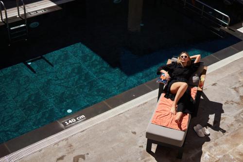 a woman sitting on a chair next to a swimming pool at Breeze Of Cappadocia in Uchisar