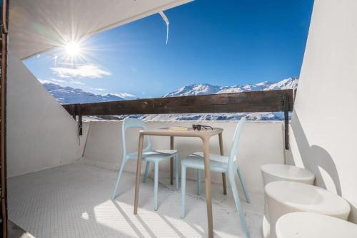 une table et des chaises sur un balcon avec vue sur les montagnes dans l'établissement Ski in ski out with sought after location, aux Menuires