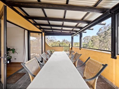 a long table and chairs in a room with windows at La Casa Gracie, Balga Sanctuary in Margaret River in Gracetown