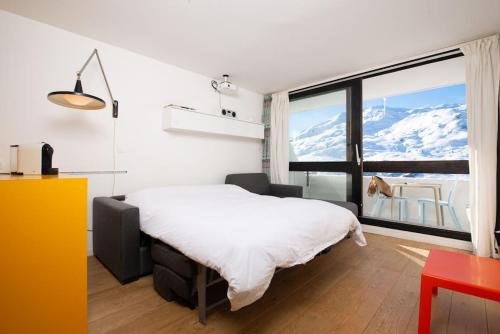 une chambre avec un lit et une grande fenêtre dans l'établissement Ski in ski out with sought after location, aux Menuires