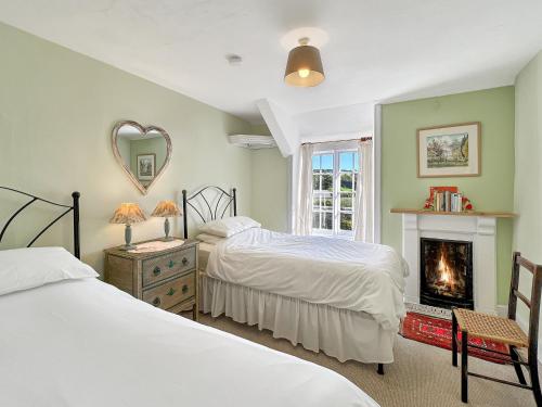 une chambre avec deux lits et une cheminée dans l'établissement Orchard Cottage, à Charles