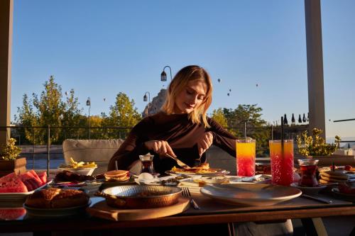 a woman sitting at a table eating food at Breeze Of Cappadocia in Uchisar