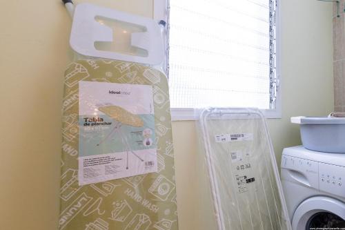 a kitchen with a washing machine and a sign on the wall at 2A Apartamento Abrigos, Wifi y balcón in Los Abrigos