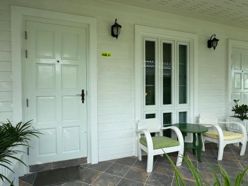a porch with white chairs and a table and a door at Pailin Pool Villa,HuaHin in Hua Hin