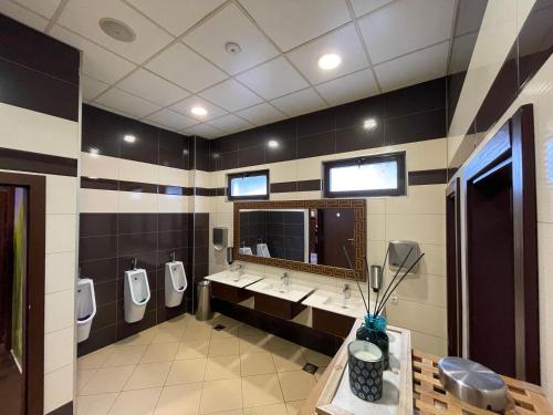 a bathroom with three urinals and three sinks and a mirror at Amazona Hotel in Pristina
