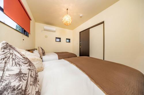a bedroom with two beds and a chandelier at 1688House美ら海 in Motobu