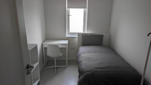 a small bedroom with a bed and a desk and a window at New House, Private Rooms in a Peaceful Neighborhood in Dublin