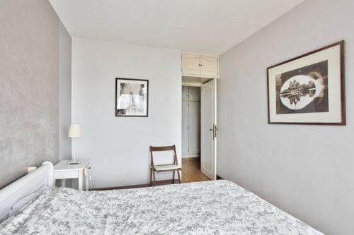 une chambre blanche avec un lit et une chaise dans l'établissement Parc des Vignoles, à Paris