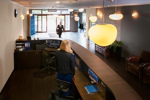 a woman standing at a bar in a office at Hotel Zawisza in Bydgoszcz