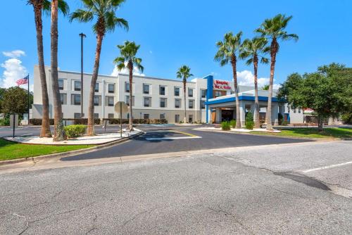 an empty street in front of a hotel with palm trees at Hampton Inn & Suites Pensacola I-10 N at University Town Plaza in Pensacola