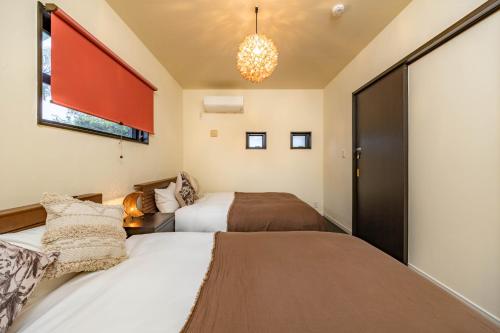 a bedroom with two beds and a chandelier at 1688House美ら海 in Motobu