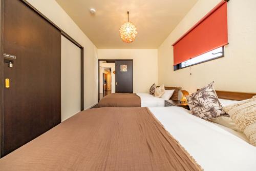 a hotel room with two beds and a chandelier at 1688House美ら海 in Motobu