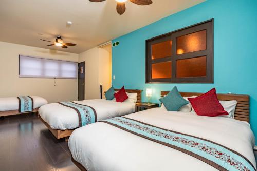 two beds in a room with blue walls at 1688House美ら海 in Motobu