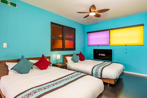 two beds in a room with blue walls at 1688House美ら海 in Motobu