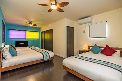 a bedroom with two beds and a ceiling fan at 1688House美ら海 in Motobu