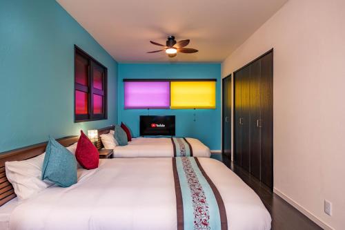 a bedroom with three beds and a flat screen tv at 1688House美ら海 in Motobu