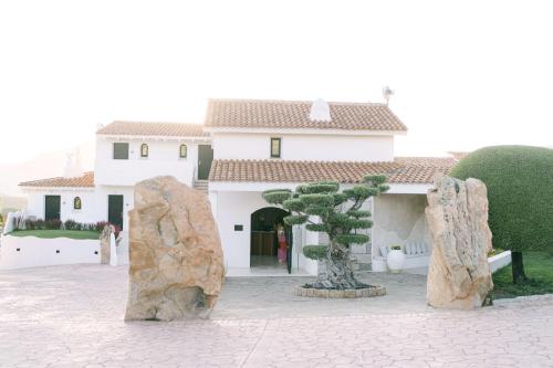 a building with a tree and two large rocks at Sulià House Porto Rotondo, Curio Collection by Hilton in Porto Rotondo