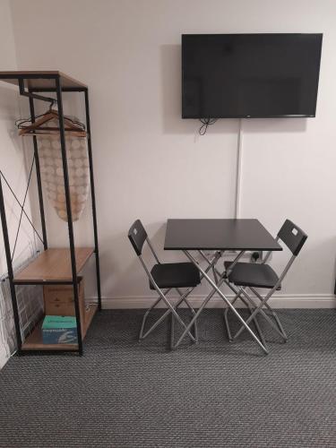 a table and chairs with a television on a wall at Gosford Park Studio 6 - Coventry in Coventry