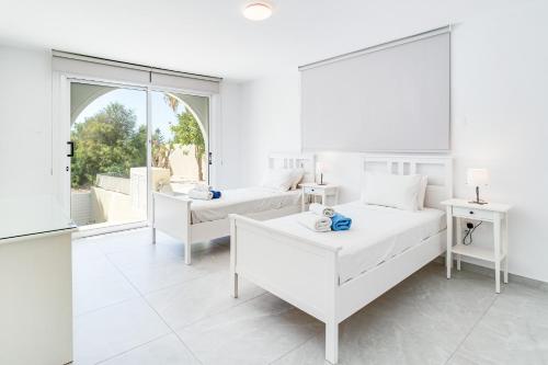 ein weißes Zimmer mit 2 Betten und einem Sofa in der Unterkunft Villa Bettina By Ezoria Villas in Coral Bay