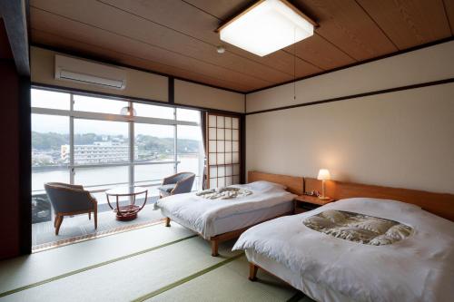 a bedroom with two beds and a large window at Hita Onsen Kizantei Hotel in Hita