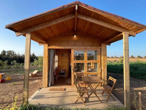 a wooden pavilion with a table and chairs in a field at Countryside's Tiny House in O Ben Slimane