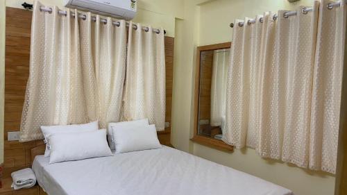 een slaapkamer met 2 bedden en een raam met gordijnen bij Nisarga Jagannath Manor in Bellary