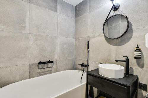 une salle de bain avec une baignoire, un lavabo et un miroir dans l'établissement Bluestay 9 - Charmant appartement à Paris 11, à Paris