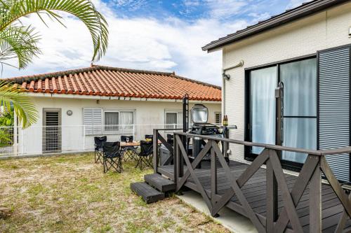 a backyard with a wooden deck and a house at 1688House美ら海 in Motobu