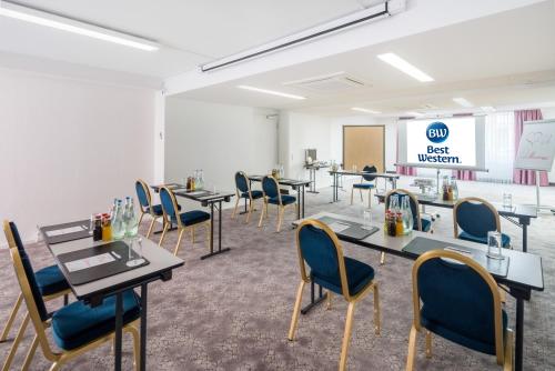 a meeting room with tables and chairs and a screen at Best Western Hotel München Airport in Erding