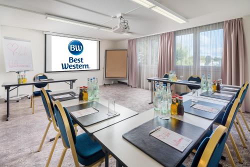 a meeting room with tables and chairs and a whiteboard at Best Western Hotel München Airport in Erding