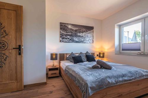 a bedroom with a large bed and a window at Apartamenty Tatrzańskie Wzgórze in Poronin