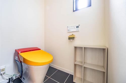 a bathroom with a toilet with a yellow lid at 1688House美ら海 in Motobu