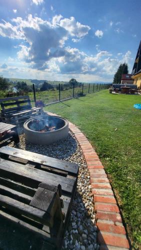 a fire pit and a bench next to a field at Dom na Ubocy in Groń