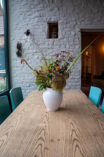 a vase filled with flowers sitting on a wooden table at La Dame Jeanne in Brakel