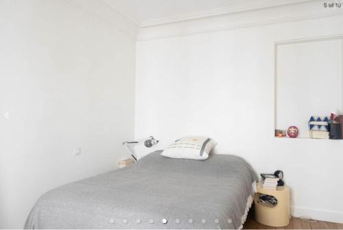 une chambre avec un lit avec une couverture grise dans l'établissement Charmant Appartement à Montmartre, à Paris
