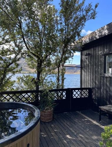 einen Whirlpool auf einer Terrasse neben einem Baum in der Unterkunft Cosy lakeview cabin 45 minutes from Reykjavik in Mosfellsbær