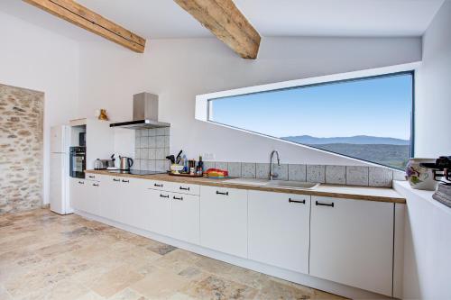 une cuisine avec des placards blancs et une grande fenêtre dans l'établissement El Madres - Charmante maison 12p vue montagne, à Joch