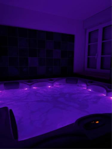 Cette chambre violette dispose d'une baignoire avec des lumières violettes. dans l'établissement La Petite Gendronnière, à Fresnes