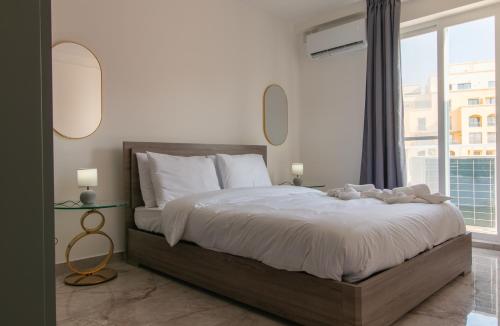 a bedroom with a large bed with a large window at Spinola Seafront Deluxe in St. Julianʼs