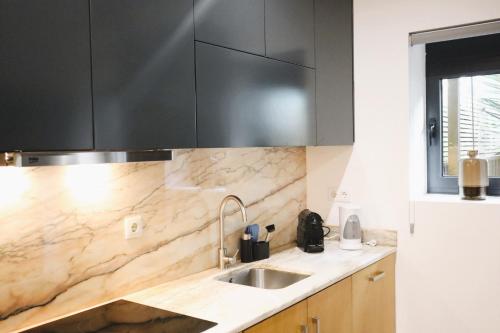 een keuken met een wastafel en zwarte kasten bij Francos Family House in Porto