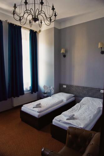 a hotel room with two beds and a chandelier at Legnicki Browar Książęcy Hotel i Restauracja in Legnica