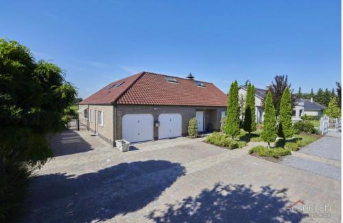 a garage with two white doors and a red roof at Puur17 in Lommel