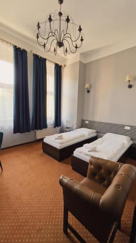 a bedroom with two beds and a couch and a chandelier at Legnicki Browar Książęcy Hotel i Restauracja in Legnica