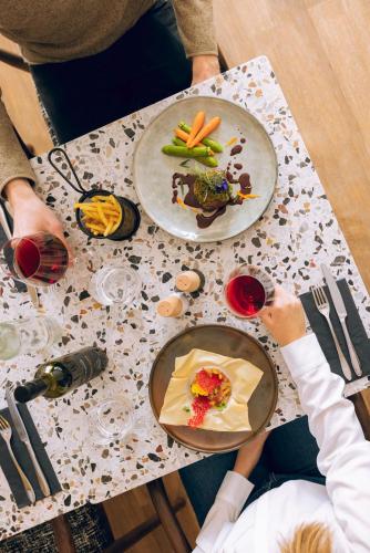 two people sitting at a table with plates of food at Hotel Valaisia Crans Montana, a Faern Collection Resort in Crans-Montana