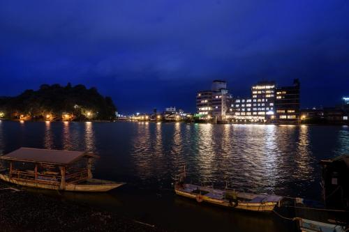 two boats are docked on a river at night at Hita Onsen Kizantei Hotel in Hita
